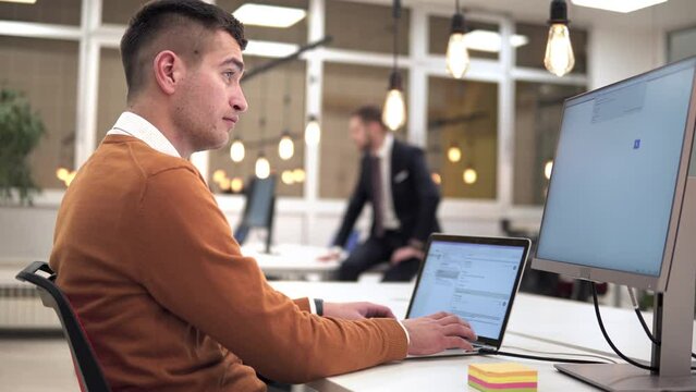 Group of diverse colleagues working on the computers in the modern office or coworking space, bearded hipster as a programmer writing code