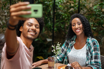 happy couple having fun and taking a selfie sitting in table