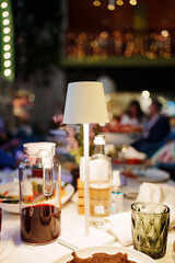 a table with a white tablecloth, glasses, crockery and decor in dark restaurant