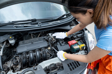 Asian woman car technician in uniform checking car engine