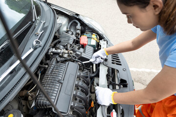 Asian woman car technician in uniform checking car engine