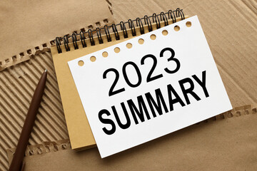 SUMMARY 2023 word on, Summary concept. text on notebook pages on brown background