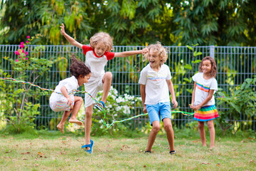 Fototapeta premium Happy kids play outdoor. Children skipping rope.