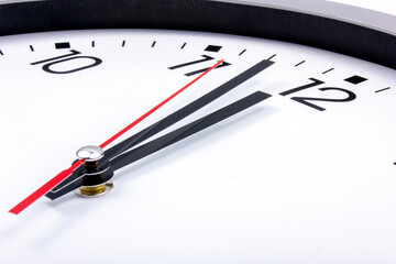 Midnight is coming. Black and white office clock with a red pointer on a gray background.