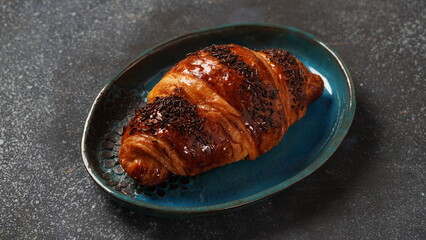 Traditional French breakfast croissant with chocolate on dark background