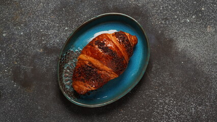 Traditional French breakfast croissant with chocolate on dark background
