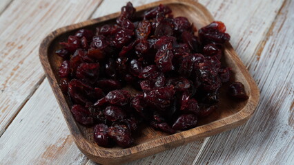 Pile of dried black raisins in a wooden tray.