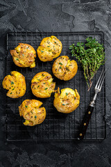 Crushed, smashed potatoes baked with rosemary and thyme. Black background. Top view