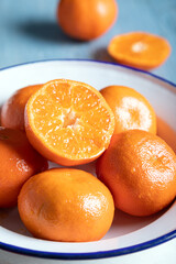 Halved and whole mandarins (tangerines). Fresh ripe whole and sliced mandarin, tangerine or clementine. Whole and halved clementines in a bowl.