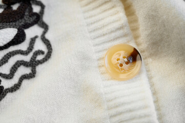 Obraz na płótnie Canvas beautiful button close-up on a sweater. Beige cardigan close-up