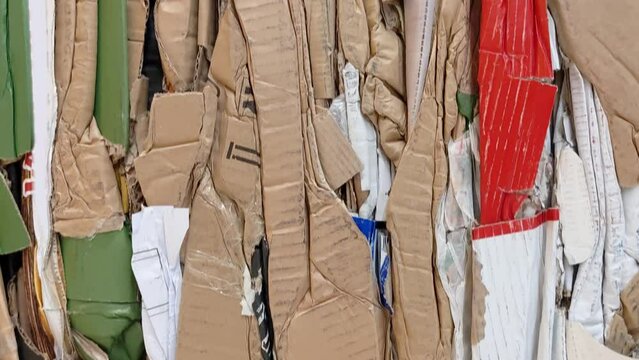 A large stack of waste paper from pressed cardboard boxes is sorted and packed for paper recycling. Sorting garbage. Secondary use of resources. Raw materials for the pulp industry.