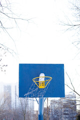 The wind shakes the basketball net. Blue basketball backboard with snow during wintertime