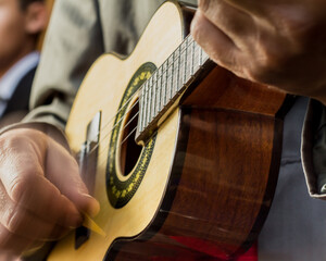 Hands of an white man playing an small samba guitar called cavaquinho or cavaco