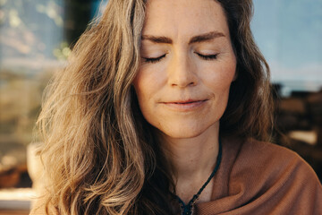 Meditation and self-healing: Mature woman practicing ayurveda at home - obrazy, fototapety, plakaty