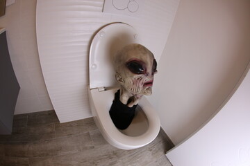 Spooky alien inside toilet bowl 