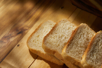 bread on the table. pieces of bread lie on a wooden board. spots of light on fresh baked goods. morning sun shines on food. High quality 4k footage
