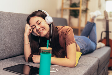 Young teen girl using digital tablet computer listening music at home