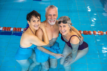 Senior man and two women standing in the water at the swimming pool