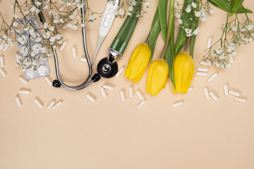Holiday medicine - stethoscope, pills and flowers on a beige background with a place for text.