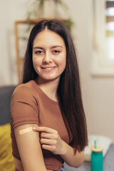 Cheerful teenage girl having plaster on arm .Virus protection. Covid-19 vaccination. HPV vaccine