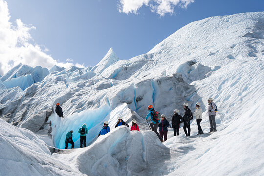 Los turistas y la gu&iacute;a est&aacute;n observando a una persona que est&aacute; en la parte alta del glaciar Perito Moreno en la Patagonia Argentina.
