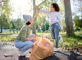 High five, volunteer woman and kid cleaning garbage pollution, waste product or community...