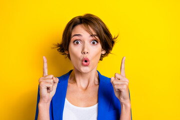 Photo of funny businesswoman wear blue jacket pouted lips crazy news direct fingers up opening cheap hotel prices isolated on yellow color background