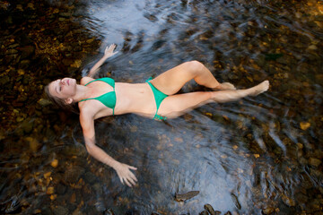 teenager girl in a bikini bathes relaxed in the summertime in a river 
