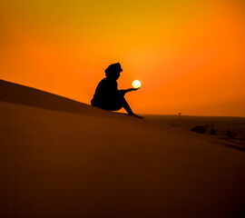 Nomad sitting in the Sands of Merzouga with the Sun in His Hands