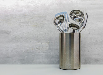 Closeup Kitchen cooking utensil tool shiny stainless spoon sets in holders set on grey kitchen table , copy space.