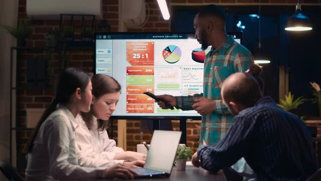 African american employee giving analytics report presentation in business meeting, showing statistics data on digital board screen. Office worker marketing research, strategy planning