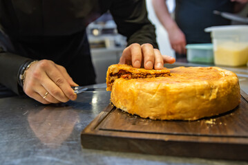 chef hand cut meat pie on restaurant kitchen