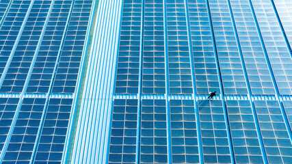 A person is checking solar panels on the roof of a building