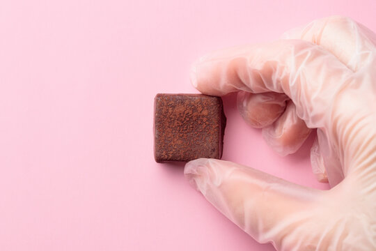 Handcrafted chocolate bonbon in a human hand in a glove