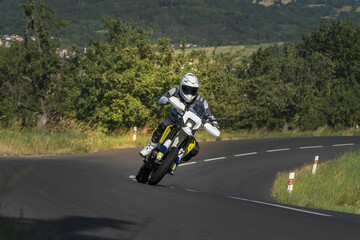 Supermoto motorcycle rider in white helmet on mountain road