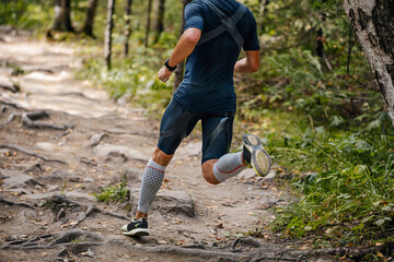 male athlete running in forest in compression calf sleeve