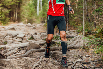 male runner run forest marathon. blood on knee after injury
