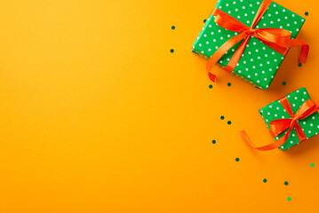 Fototapeta na wymiar Saint Patrick's Day concept. Top view photo of green gift boxes with orange ribbon bows and confetti on isolated yellow background with copyspace