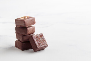 Chocolate bonbons with praline on white marble background