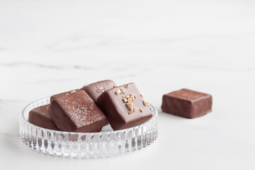 Chocolate bonbons with praline on white marble background