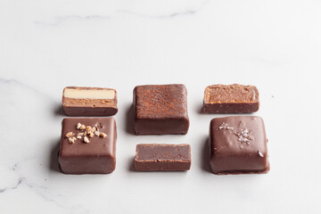 Chocolate bonbons with praline on white marble background