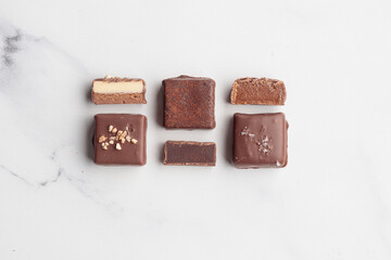 Chocolate bonbons with praline on white marble background