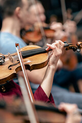 A person playing the violin or viola during a classical symphony orchestra rehearsal