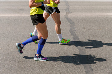 legs man and woman runners run marathon street