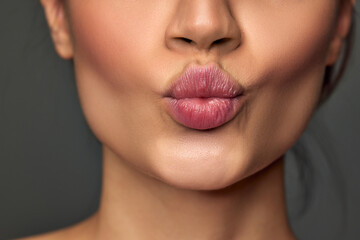 Cropped image of female face, lips, nose, chin on grey studio background. Lip augmentation, face lifting, plastic surgery. Concept of natural beauty, skin care, cosmetology, cosmetics, health, fashion