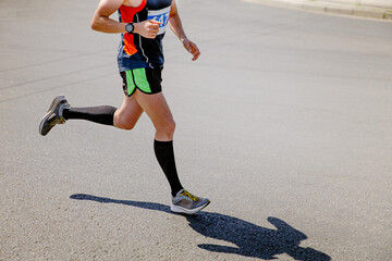 male runner in compression socks running race on asphalt