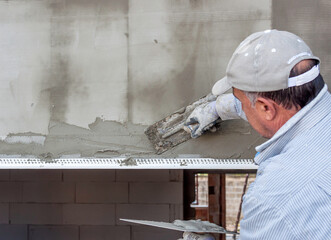 Worker applies adhesive to polystyrene panels of the facade of a residential building with an...