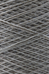 Close-up of light gray thread wound into a ball. Abstract texture