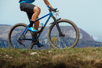 Fototapeta na wymiar closeup man on mountain bike riding trail in background of mountain