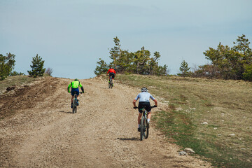 three athletes cyclists riding uphill on mountain bike